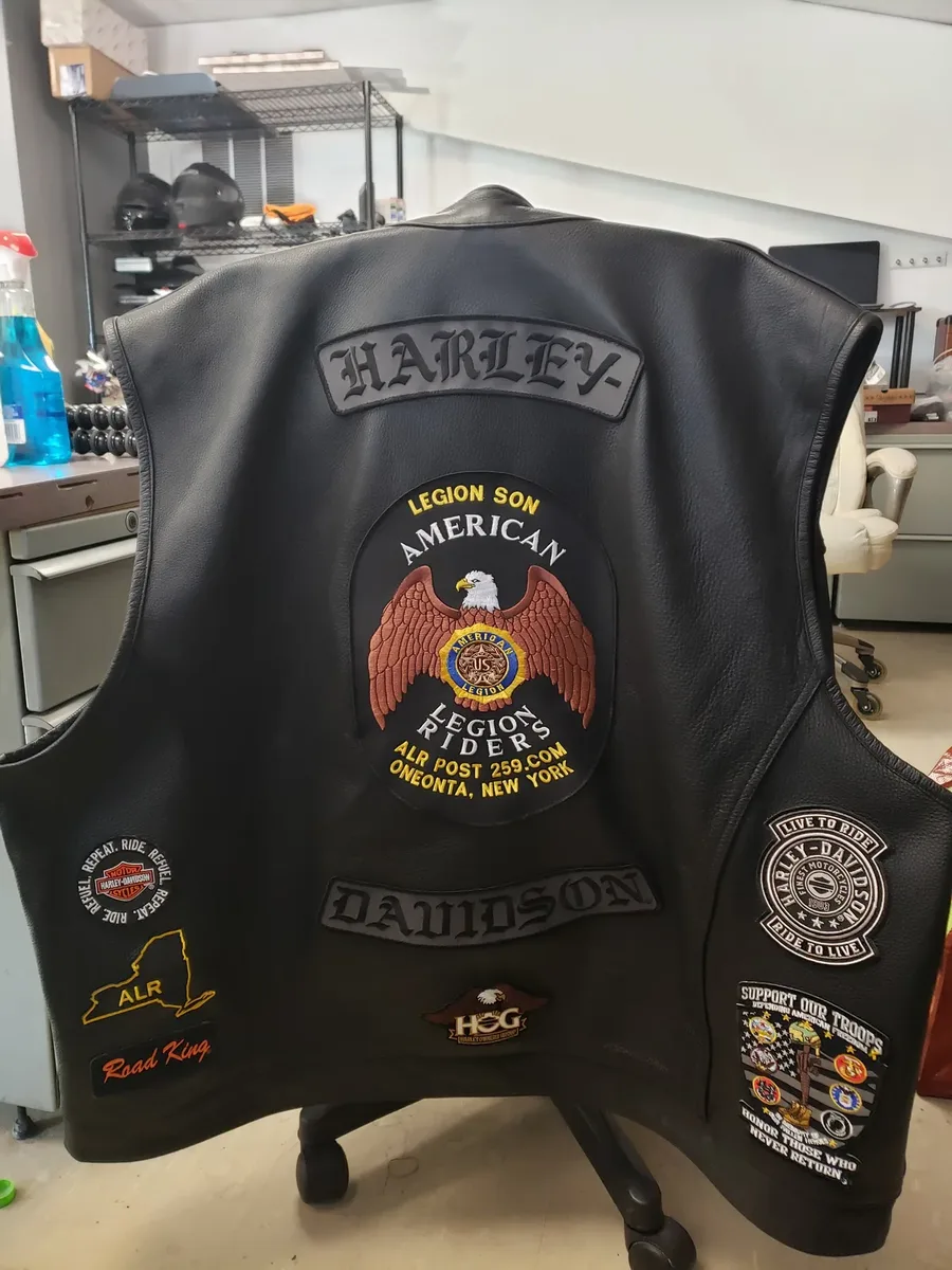 A black American Legion Riders vest on a stand, showing the ALR Post 259 Oneonta center patch, a Harley top rocker, and assorted state and Riders patches