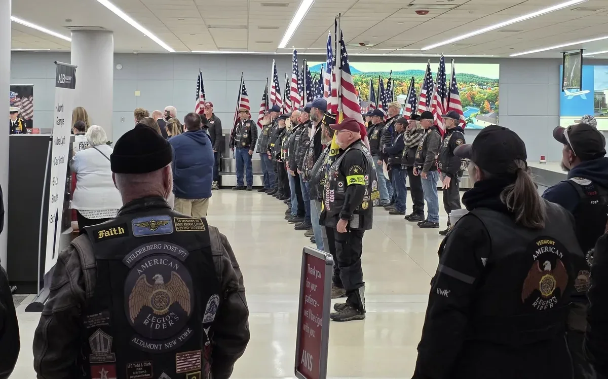 American Legion Riders in vests holding a flag line inside the airport terminal for an Honor Flight departure