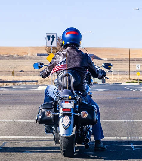 A motorcyclist riding with an American flag mounted on the motorcycle