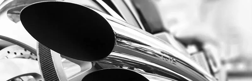 Close-up of chrome motorcycle exhaust pipes and the rear wheel