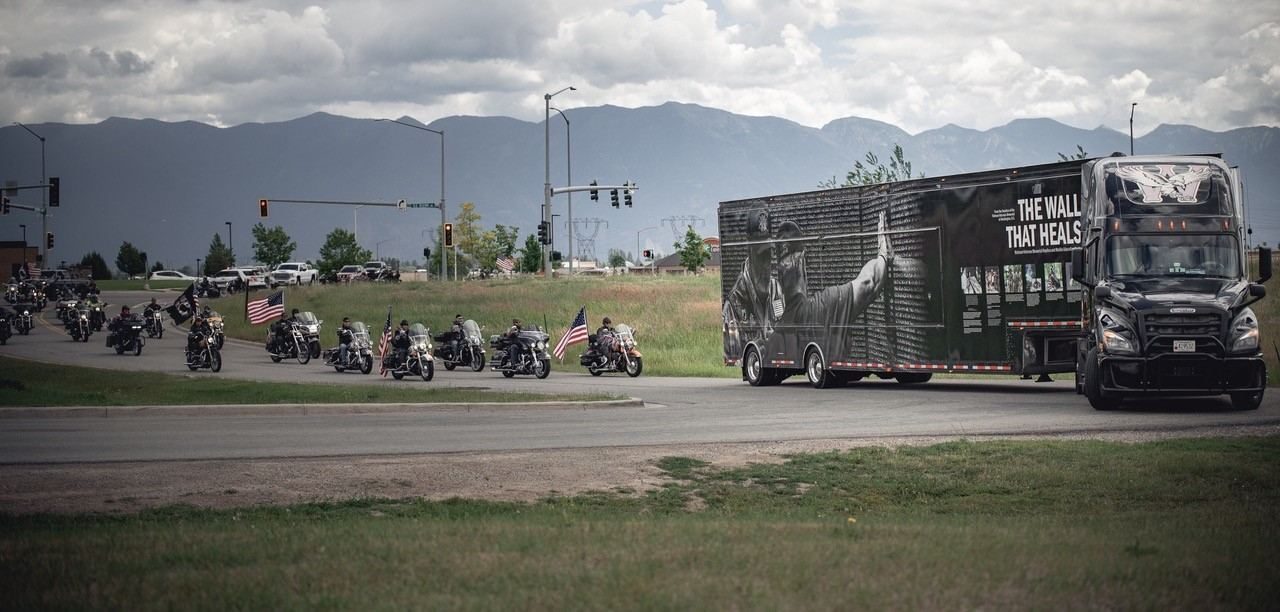 A long line of motorcycles escorting The Wall That Heals truck and trailer