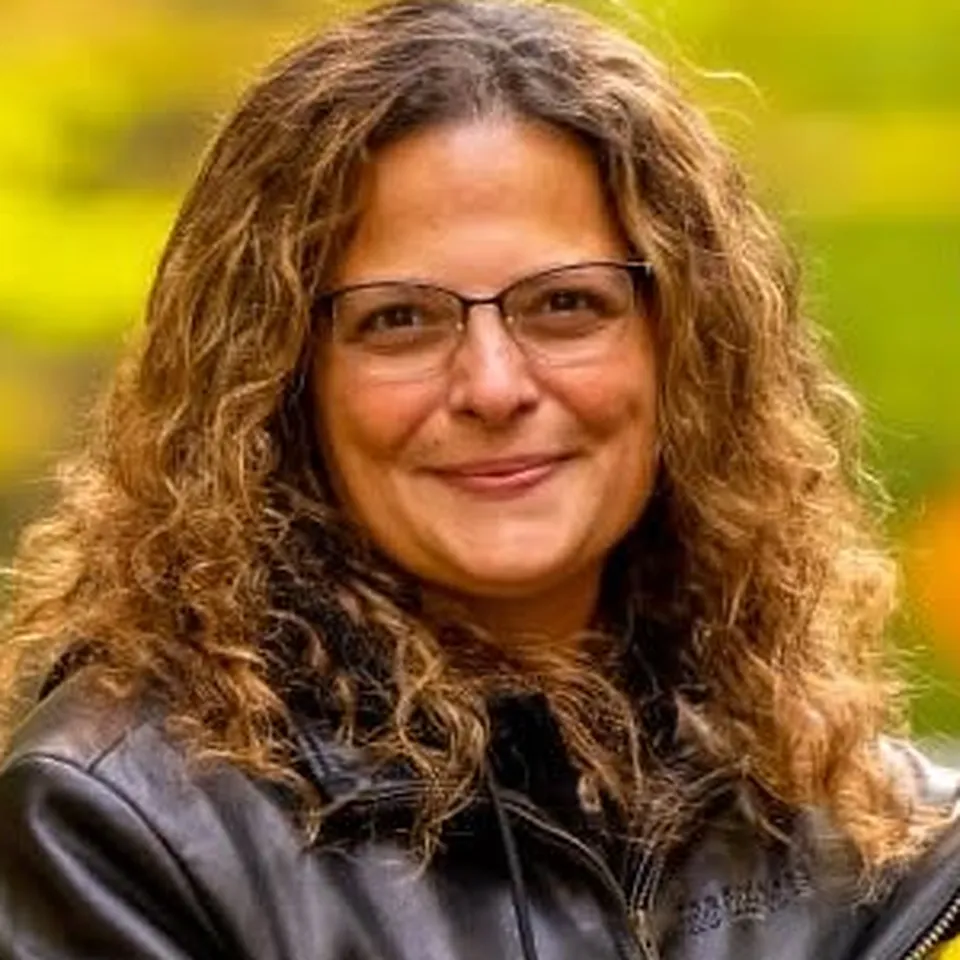 Angela Apostolakis, Historian of ALR Post 259, in her leather jacket outdoors among fall foliage