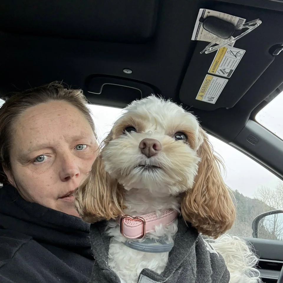 Deb Dennis holding Bailey in a gray coat inside a car