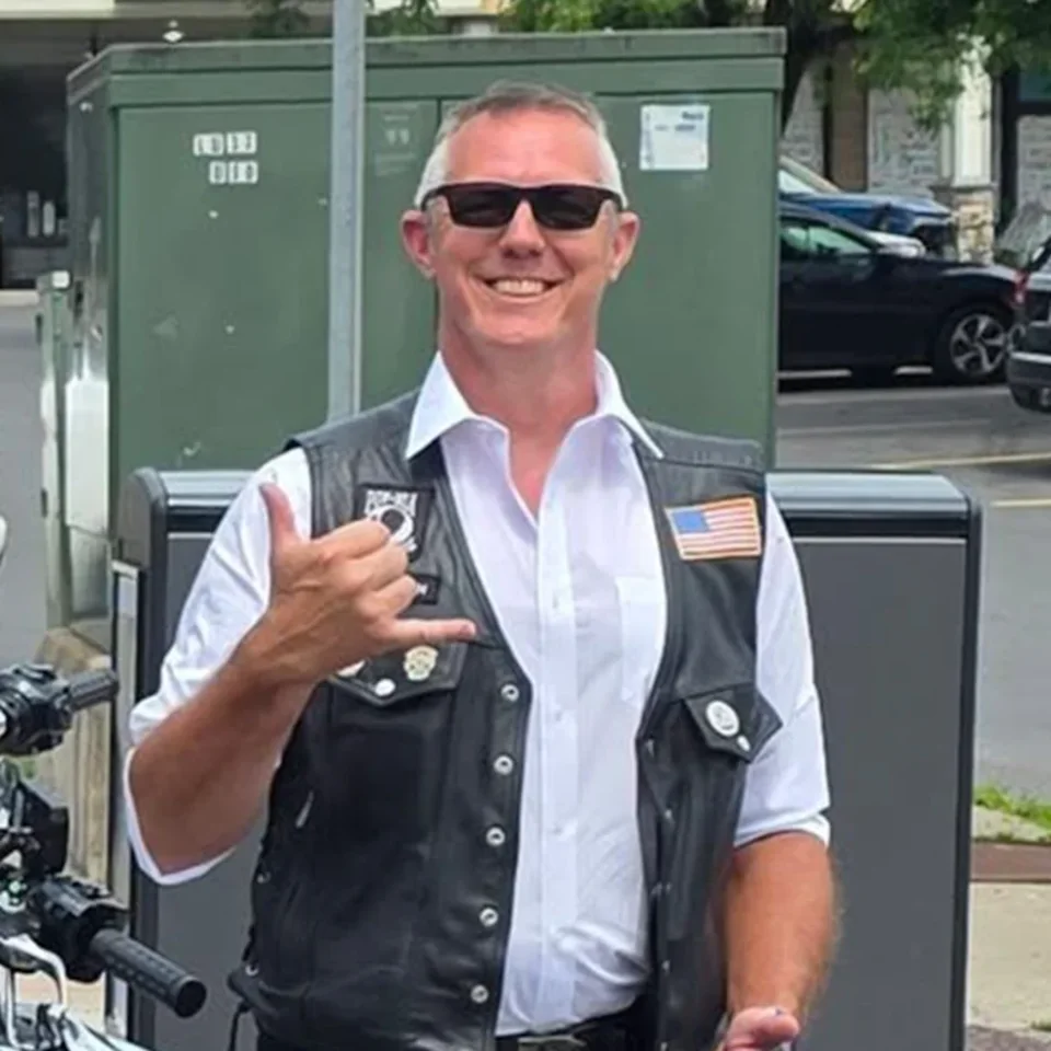 Brendan Brigham, Road Captain of ALR Post 259, in his leather vest beside his motorcycle