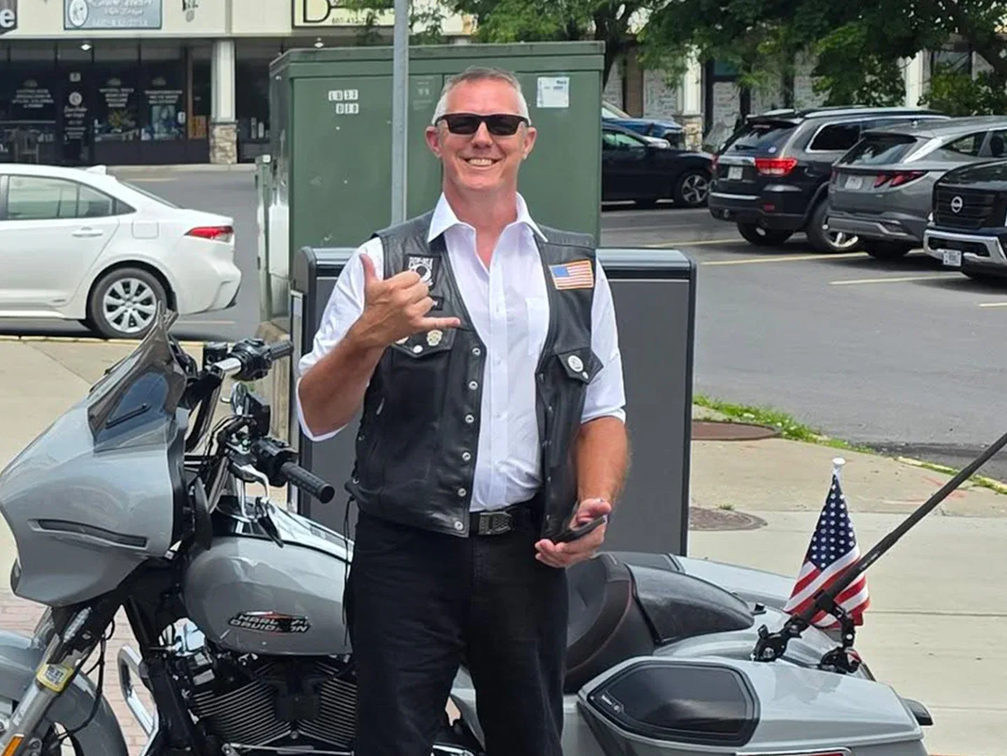 Brendan Brigham standing beside his grey 2024 Harley-Davidson Street Glide with an American flag on the back