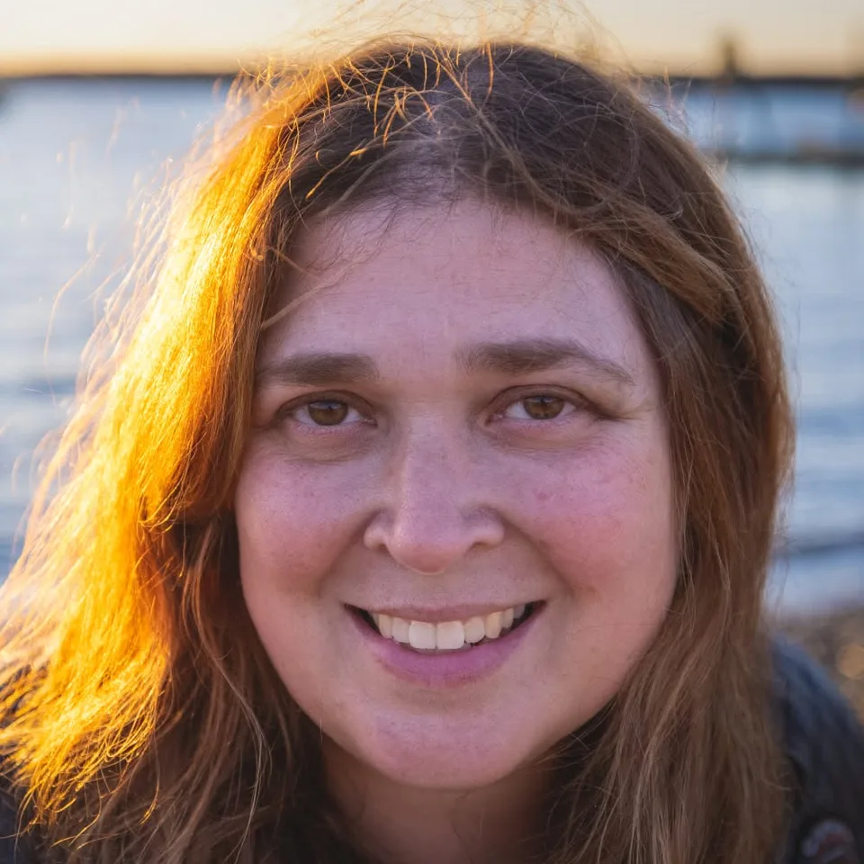Charlotte Chase, Secretary of ALR Post 259, smiling by the water at sunset