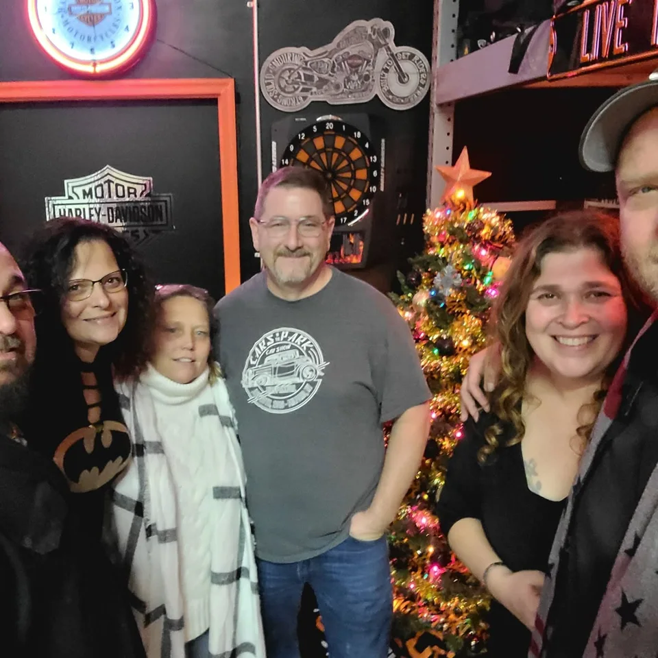 Chris and Deb Dennis posing with friends inside a motorcycle-themed bar