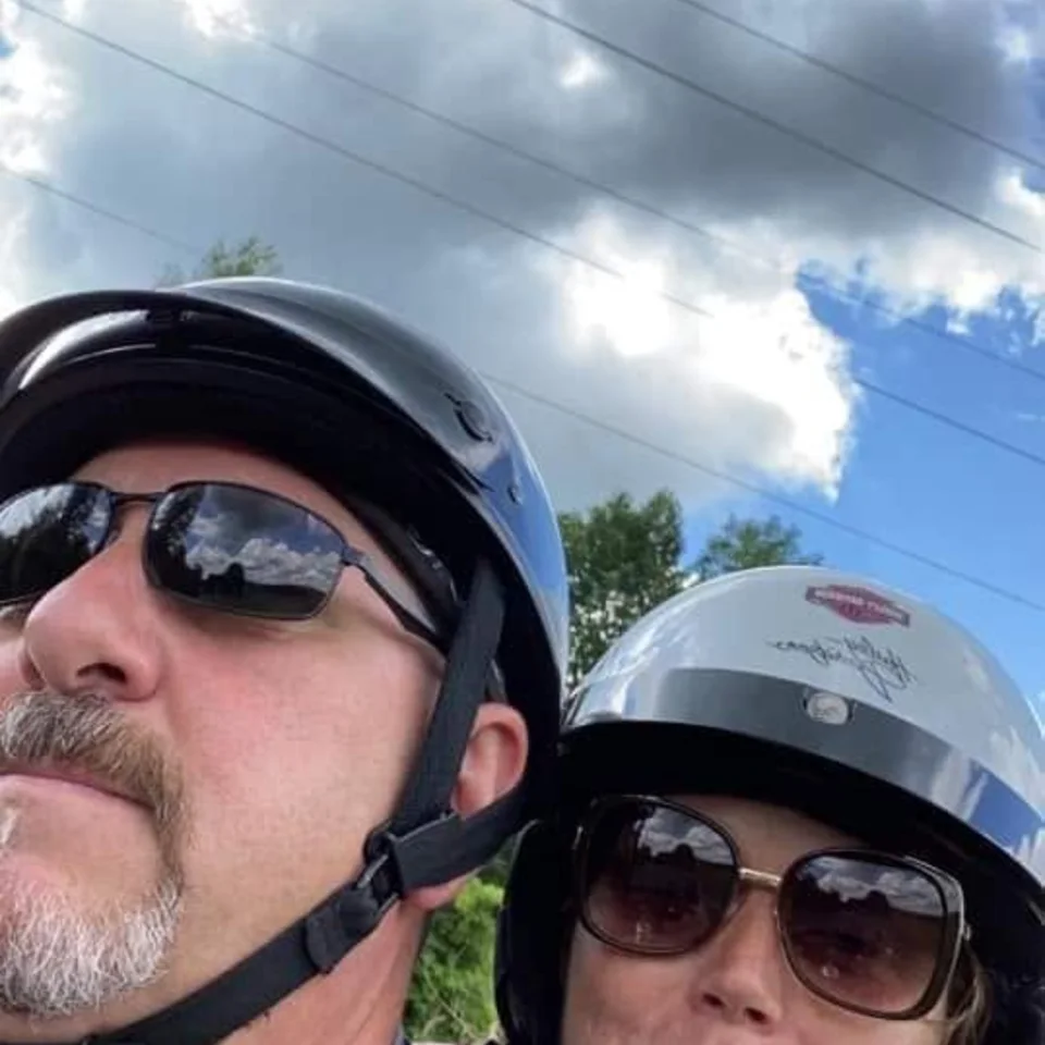 Chris and Deb Dennis taking a selfie in their motorcycle helmets