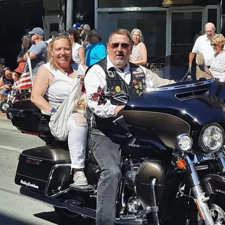 Chris and Deb Dennis riding their Harley-Davidson in a motorcycle procession
