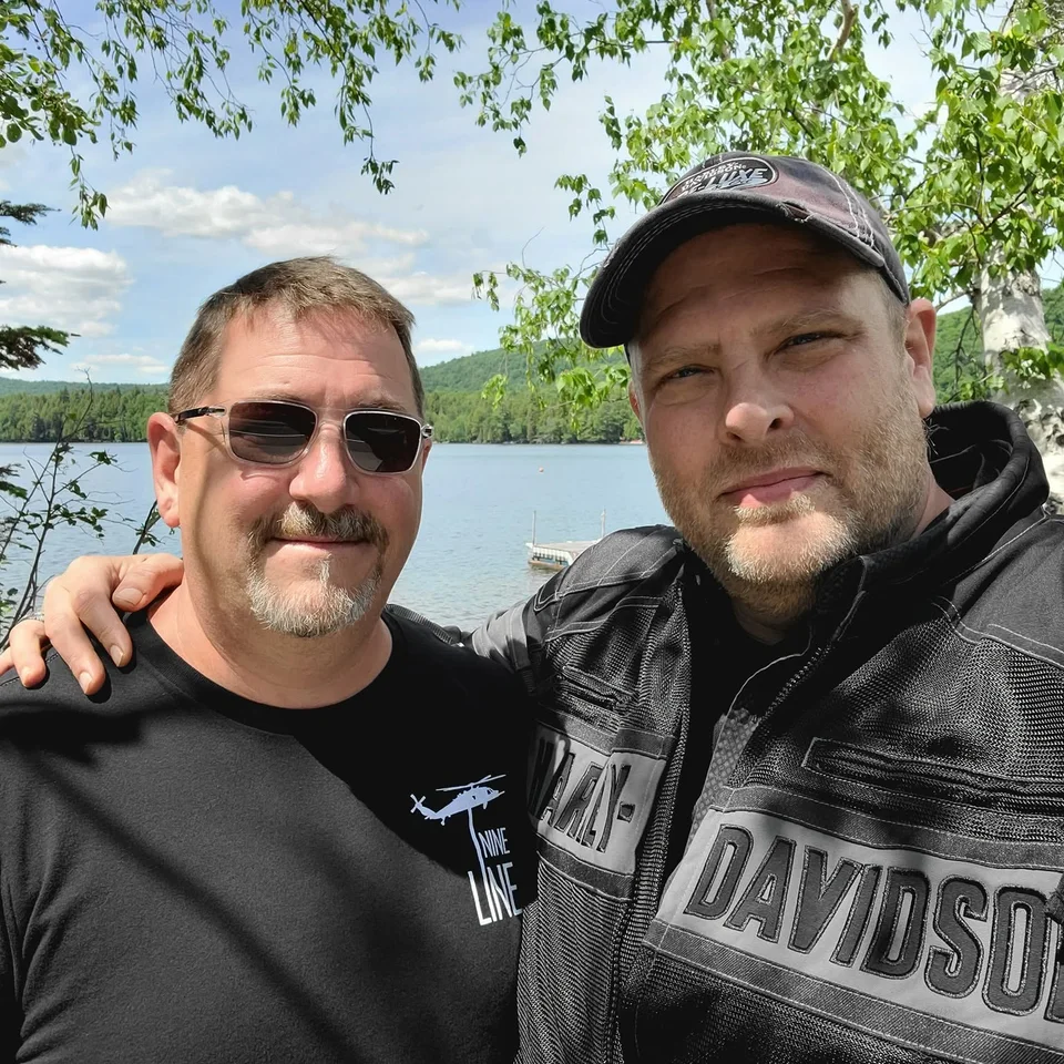 Chris Dennis and a friend in riding gear beside a lake