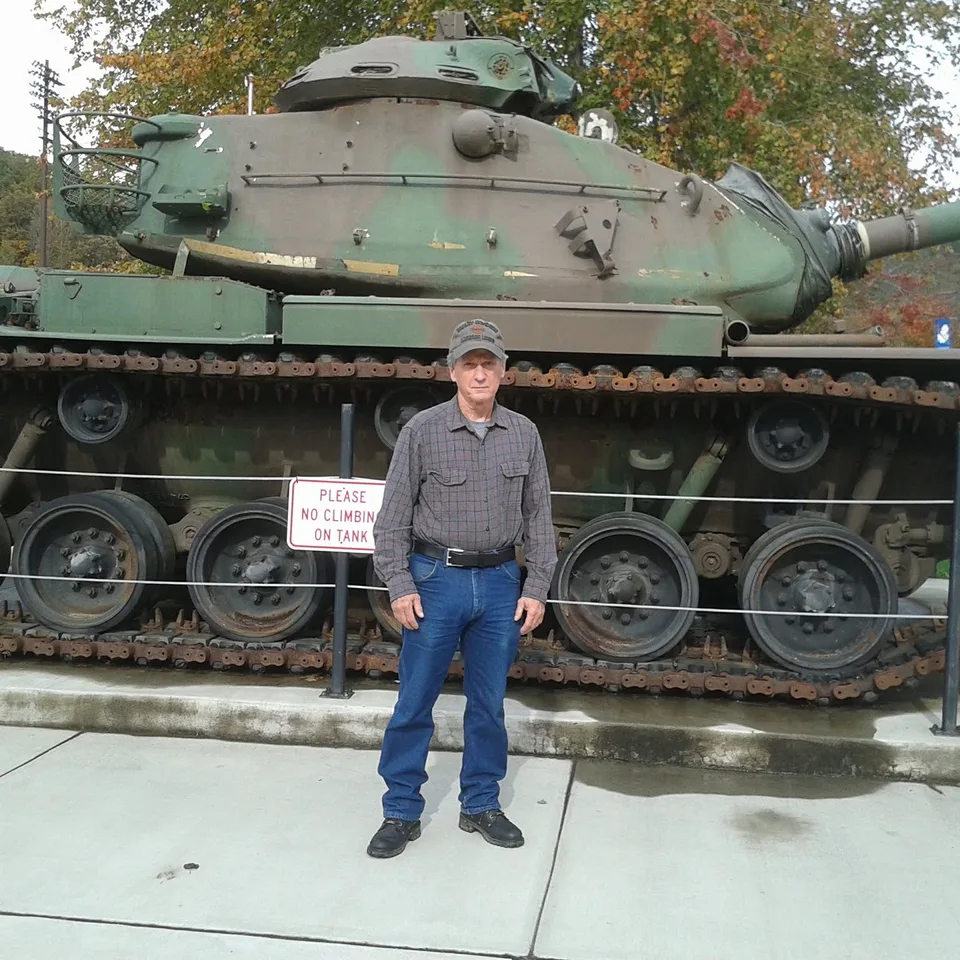 David Buck standing in front of a military tank at a museum