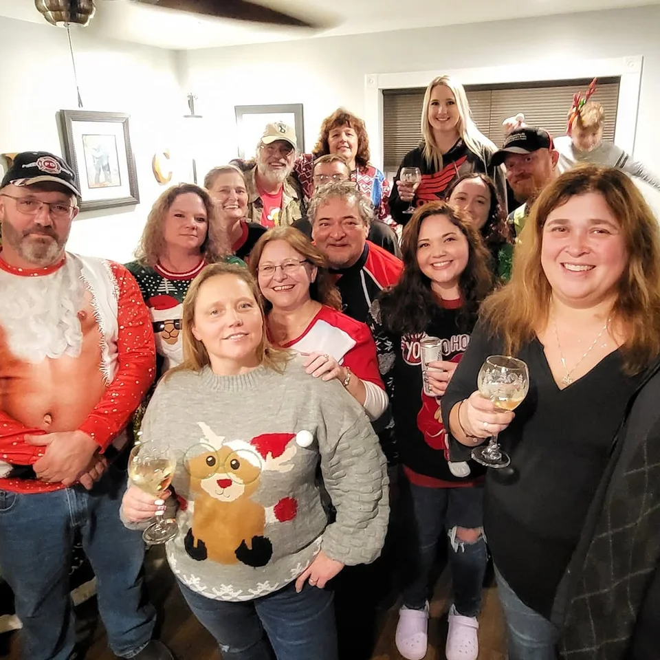 Deb Dennis posing with a group of friends at an indoor holiday gathering