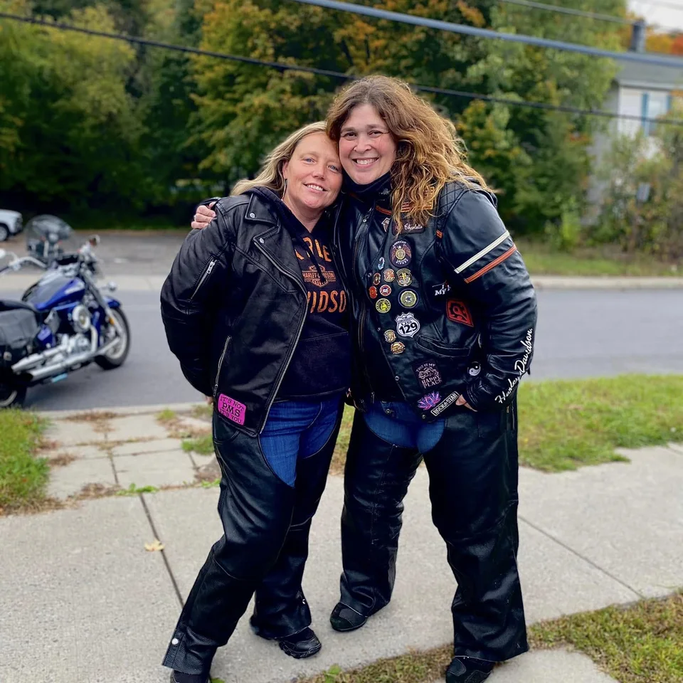 Deb Dennis standing with a friend in riding gear beside parked motorcycles