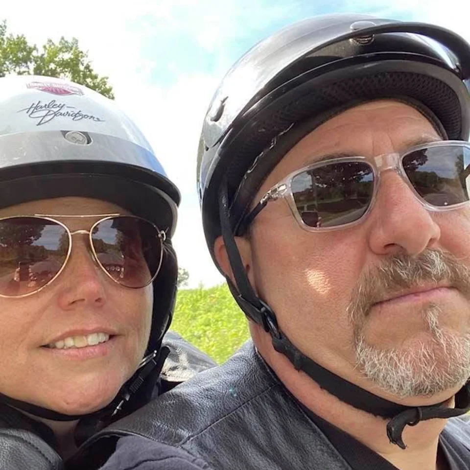Deb and Chris Dennis taking a close-up selfie in their motorcycle helmets