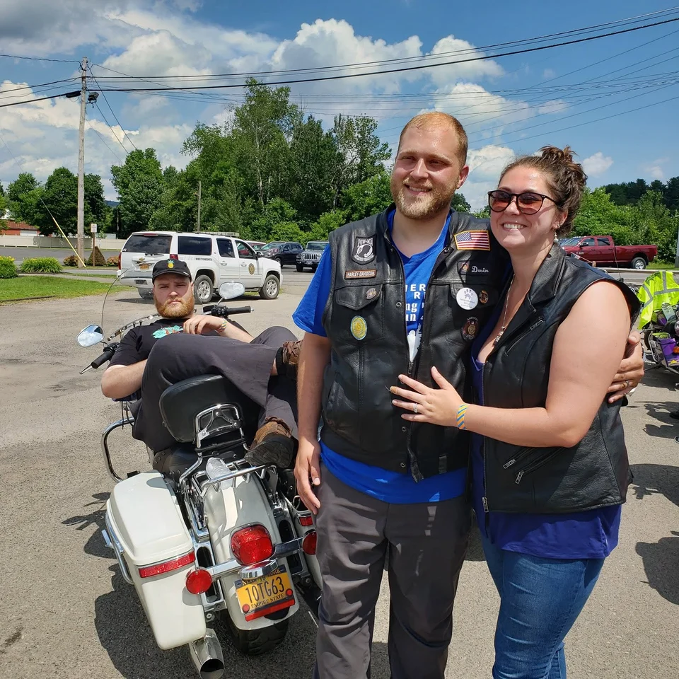 Devin Chase and Rebecca Chase standing together beside a motorcycle at an outdoor event