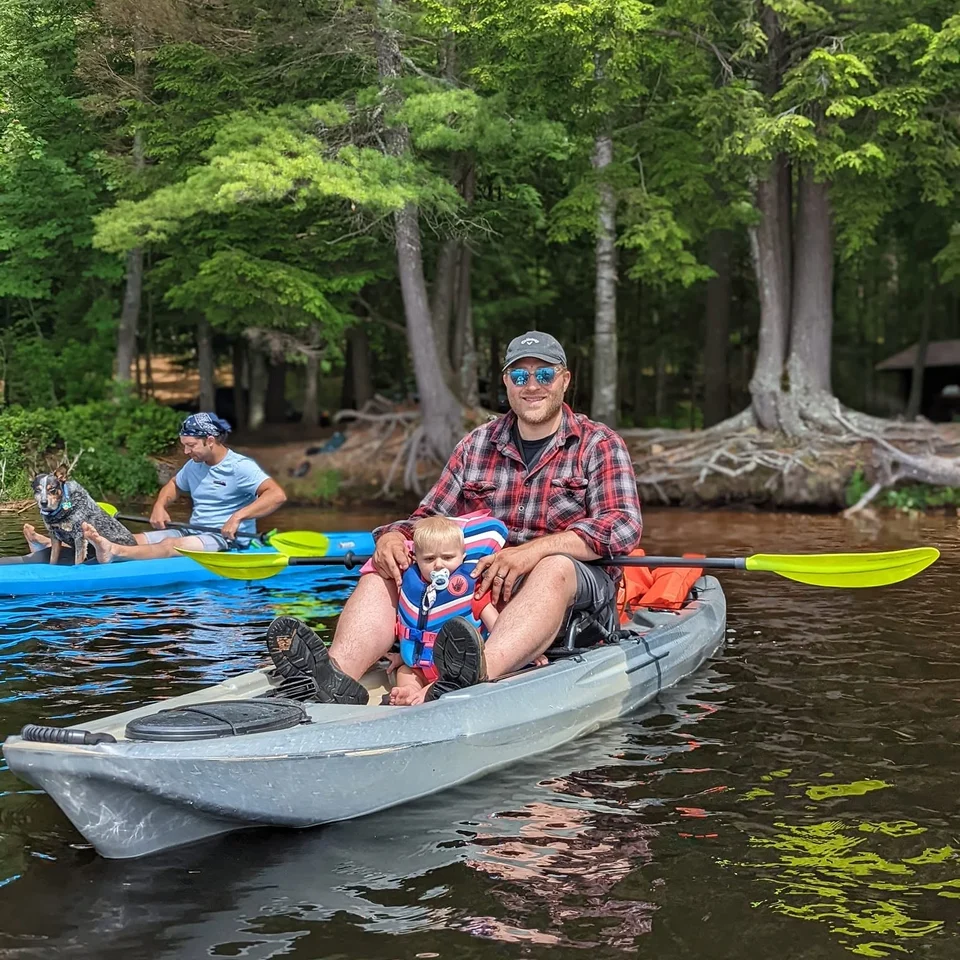 Devin Chase kayaking with a child on a wooded lake