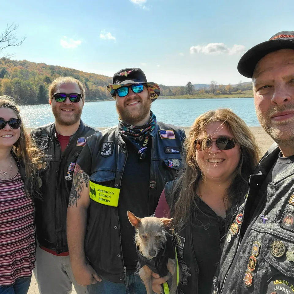 Devin Chase with family members and a small dog beside a lake