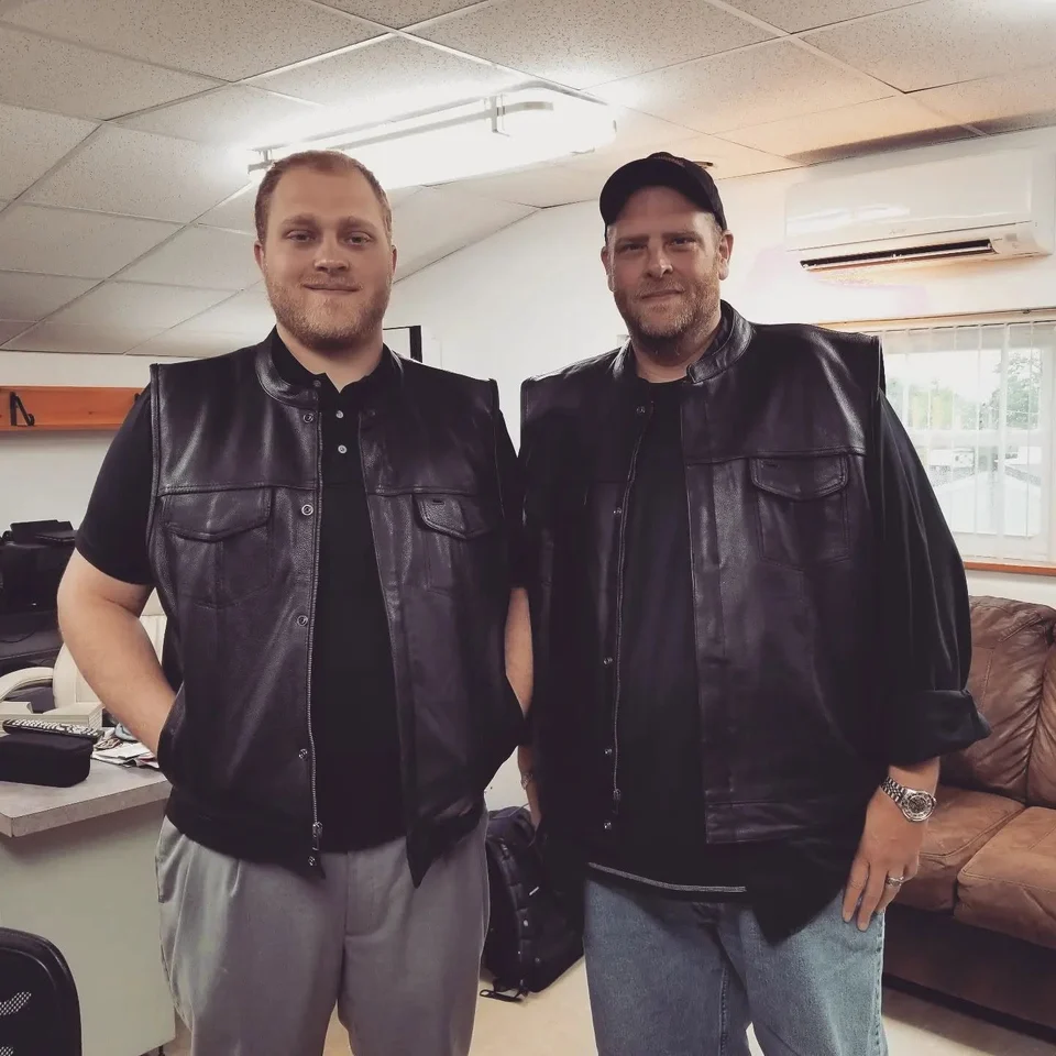 Devin Chase standing indoors with another man in a motorcycle vest