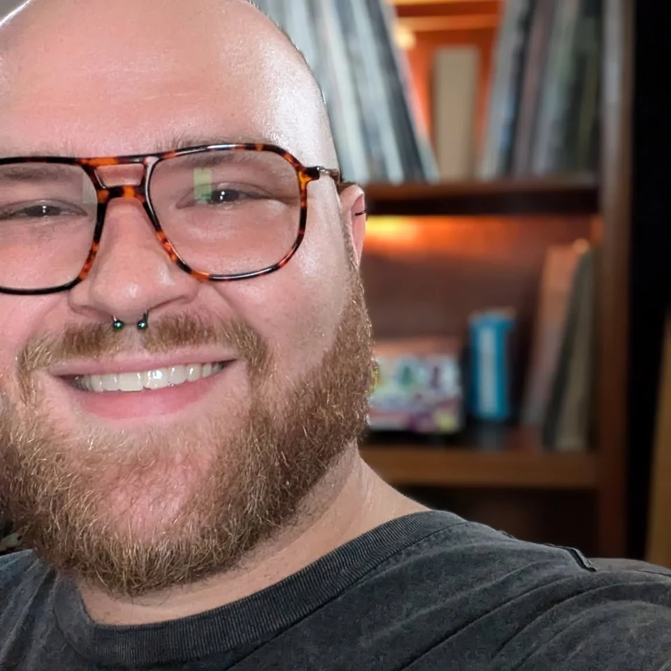 Dillon Chase smiling in glasses with a record collection behind him