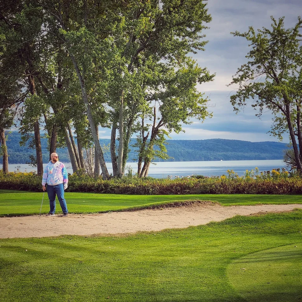 Dillon Chase standing beside a sand trap on a lakeside golf course