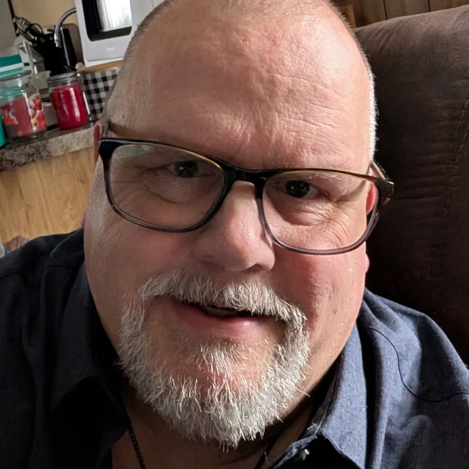 John Creaser wearing glasses and smiling at the camera