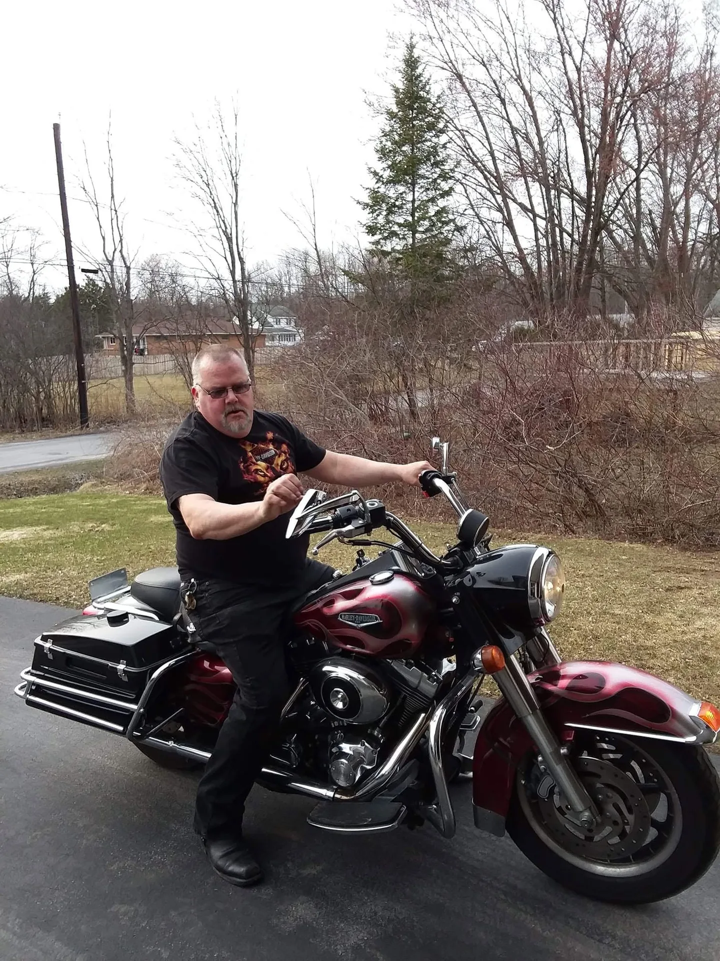John Creaser sitting on a red and black Harley-Davidson motorcycle