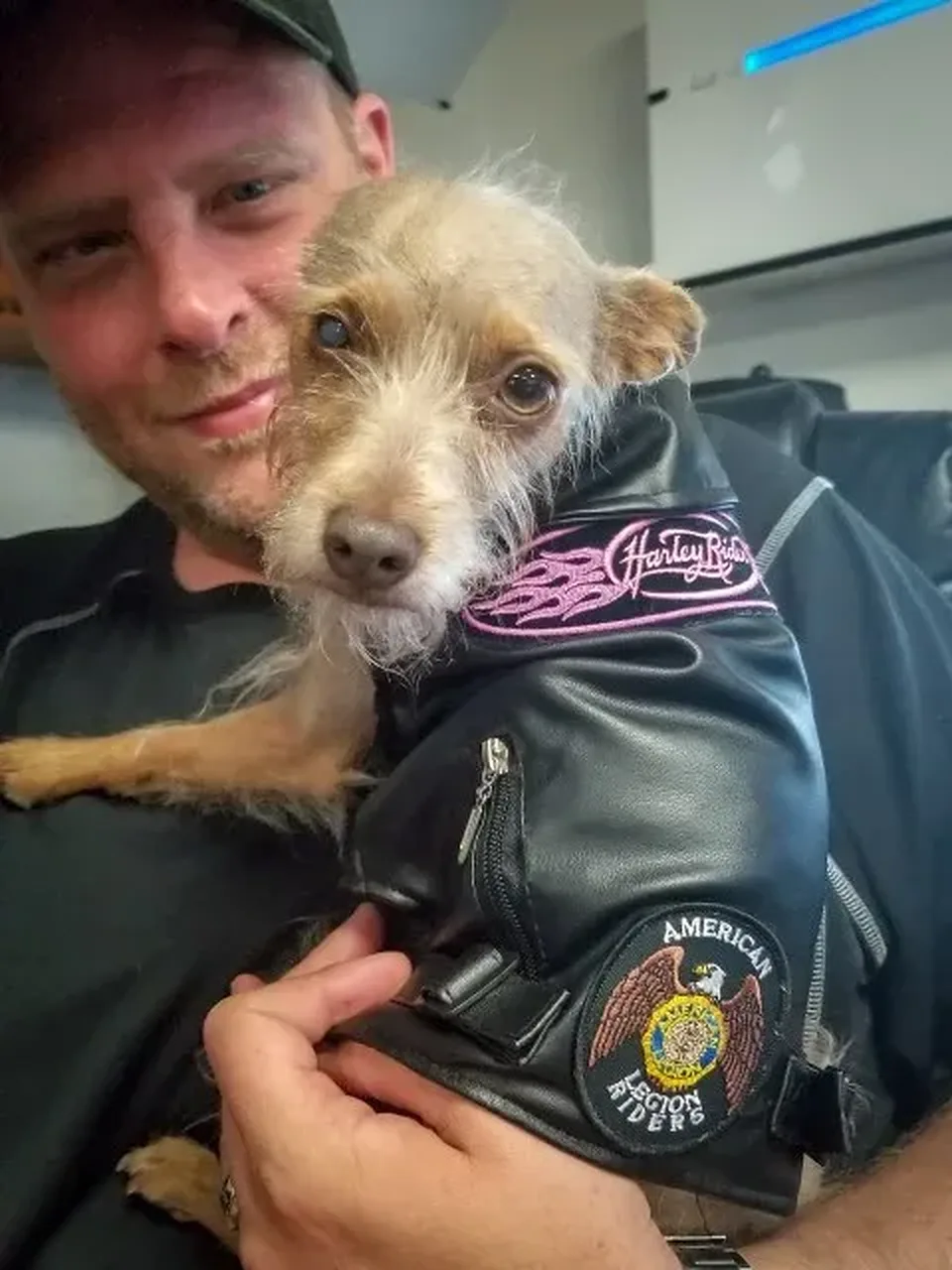 Pixel in her black leather vest, with its Harley Rider and American Legion Riders patches, held close by Chris Chase