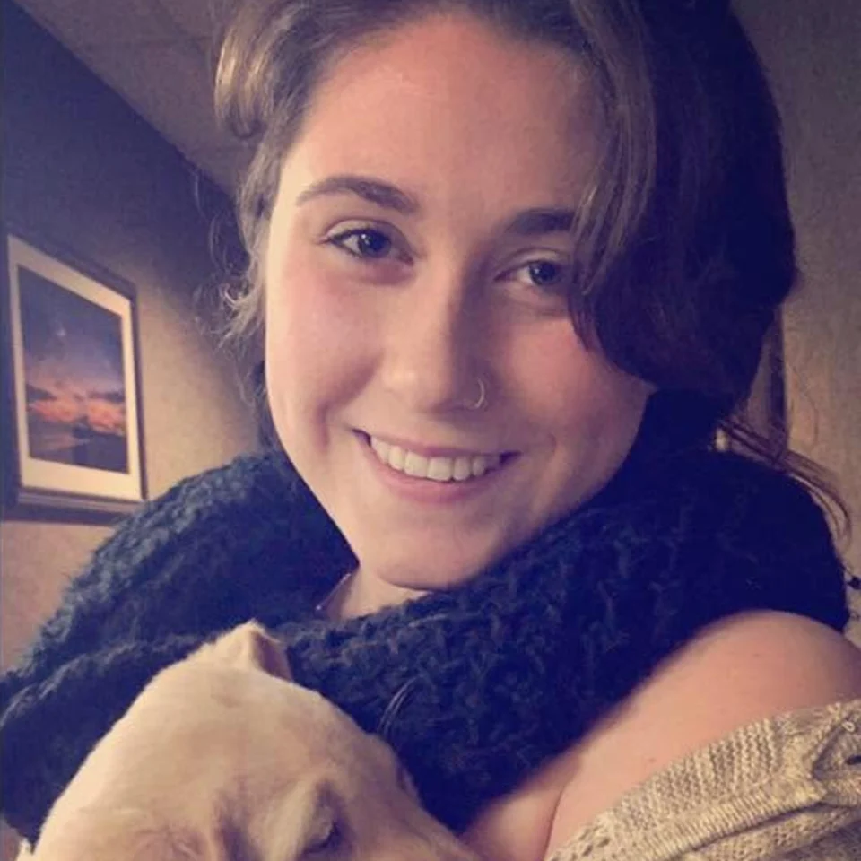 Rebecca Chase smiling while holding a sleeping puppy