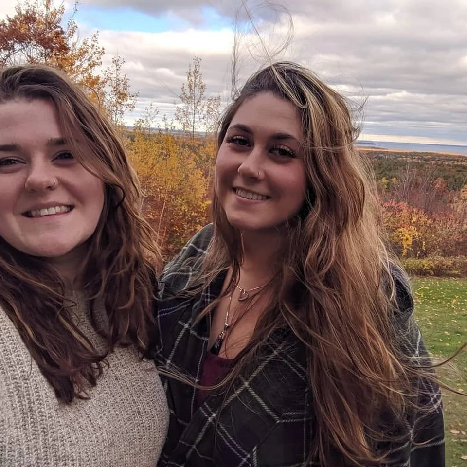 Rebecca Chase and a friend smiling at an overlook surrounded by autumn foliage