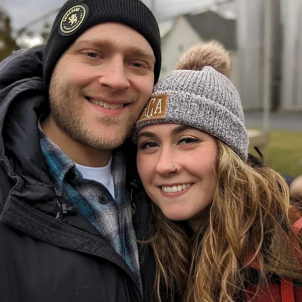 Rebecca Chase and her husband smiling together in winter hats and coats