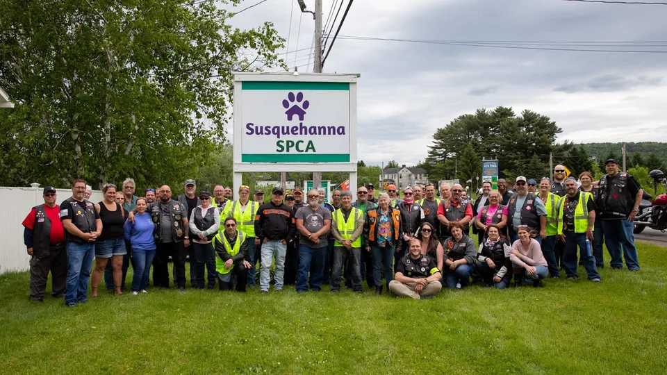 Riders and volunteers gathered in front of the Susquehanna SPCA sign after the Vets for Pets Run