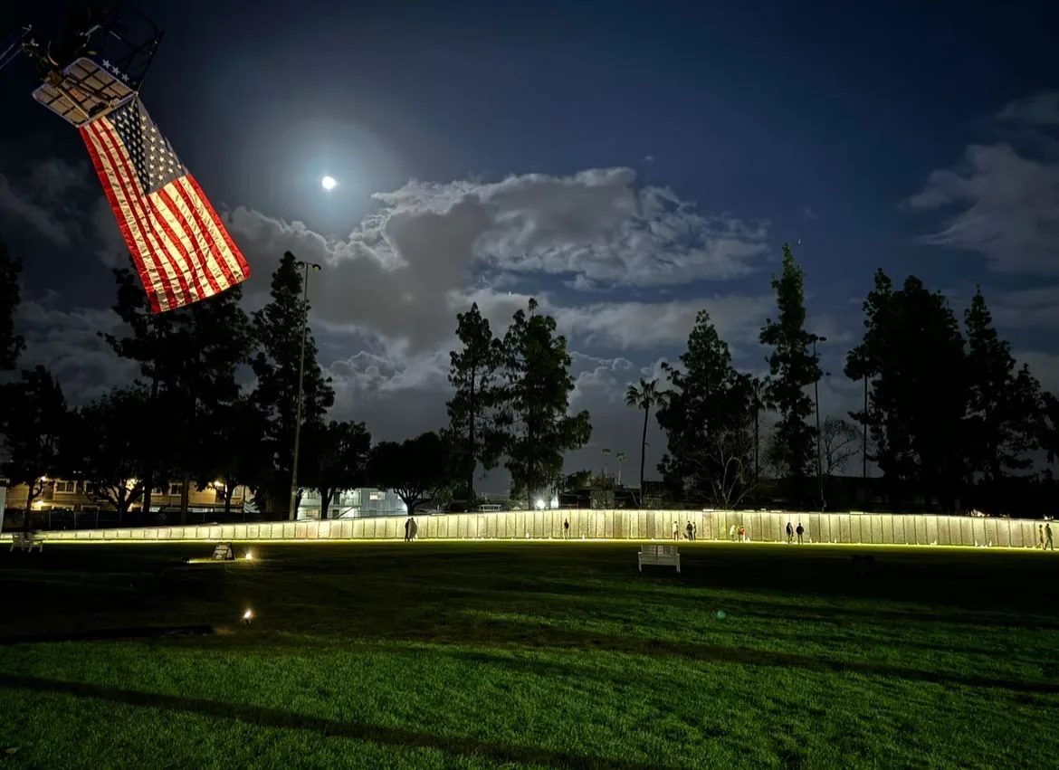 The Wall That Heals lit at night beneath a moonlit sky