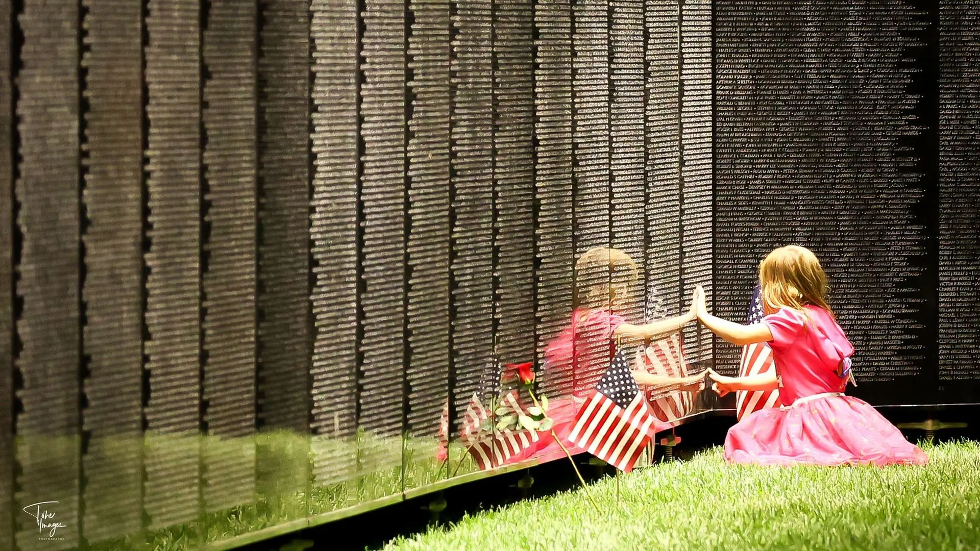 A young girl stands at the apex of The Wall That Heals, looking up at the panels